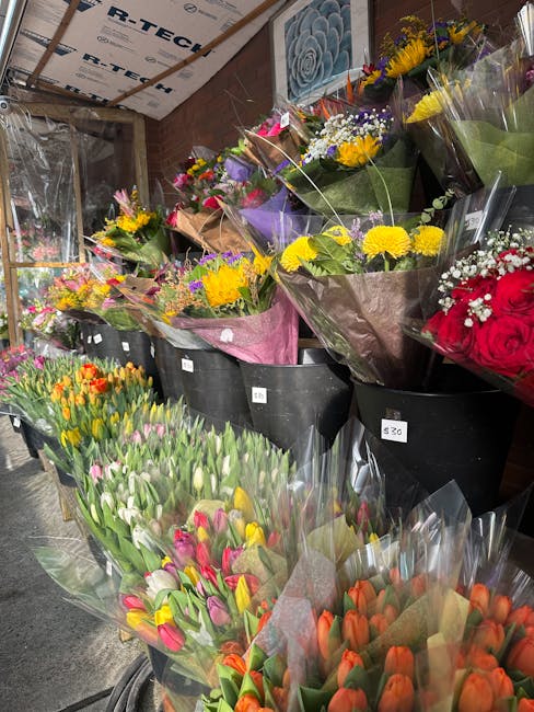 A display of freshly arranged flower bouquets at Crouch End Florist, showcasing a diverse variety of blooms including pink and white tulips, yellow daisies, purple irises, and red roses, all wrapped i