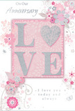 This anniversary card offers a gentle celebration of long-lasting romance, as if designed for a couple sharing a peaceful evening just off Crouch End Broadway. Its colours are soft and comforting: pastel pinks and silvery greys set against a muted rosy background, creating a sense of intimacy and warmth. The focal point is the word LOVE, spelled out in raised, velvety glitter that seems to glow lightly, with the letter O transformed into a shimmering silver heart textured to echo the feel of a cherished keepsake. Encircling this centrepiece, clusters of delicate blooms unfurl in blush, mauve, and pale ivory tones, their edges softened like watercolour petals, yet defined by graceful line work. Slender stems and swirling vines thread between the flowers, giving the composition a natural flow reminiscent of a hand-tied bouquet just delivered from a local florist. Tiny details-scattered petals, looping flourishes, and soft butterfly silhouettes-add a playful elegance and a sense of quiet motion, as though a light spring breeze is moving through the design. Above and below the central motif, phrases such as On Our Anniversary and I love you today and always appear in understated, flowing script, the letters curved with care to match the card's romantic tone. The overall impression is one of affection that has deepened over time-like years spent together in a Crouch End home, surrounded by familiar streets and little daily rituals. It feels like a keepsake meant to be tucked away and revisited, a paper echo of shared journeys, whispered promises, and the enduring comfort of true companionship.